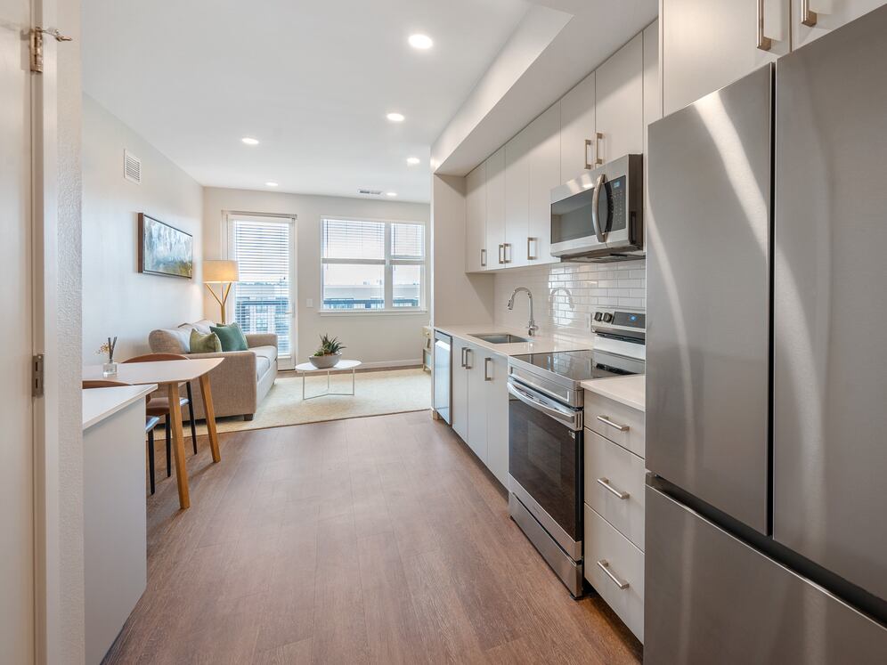 Finish Scheme II kitchen with light cabinetry, eggshell quartz countertops, white tile backsplash and stainless steel appliances.