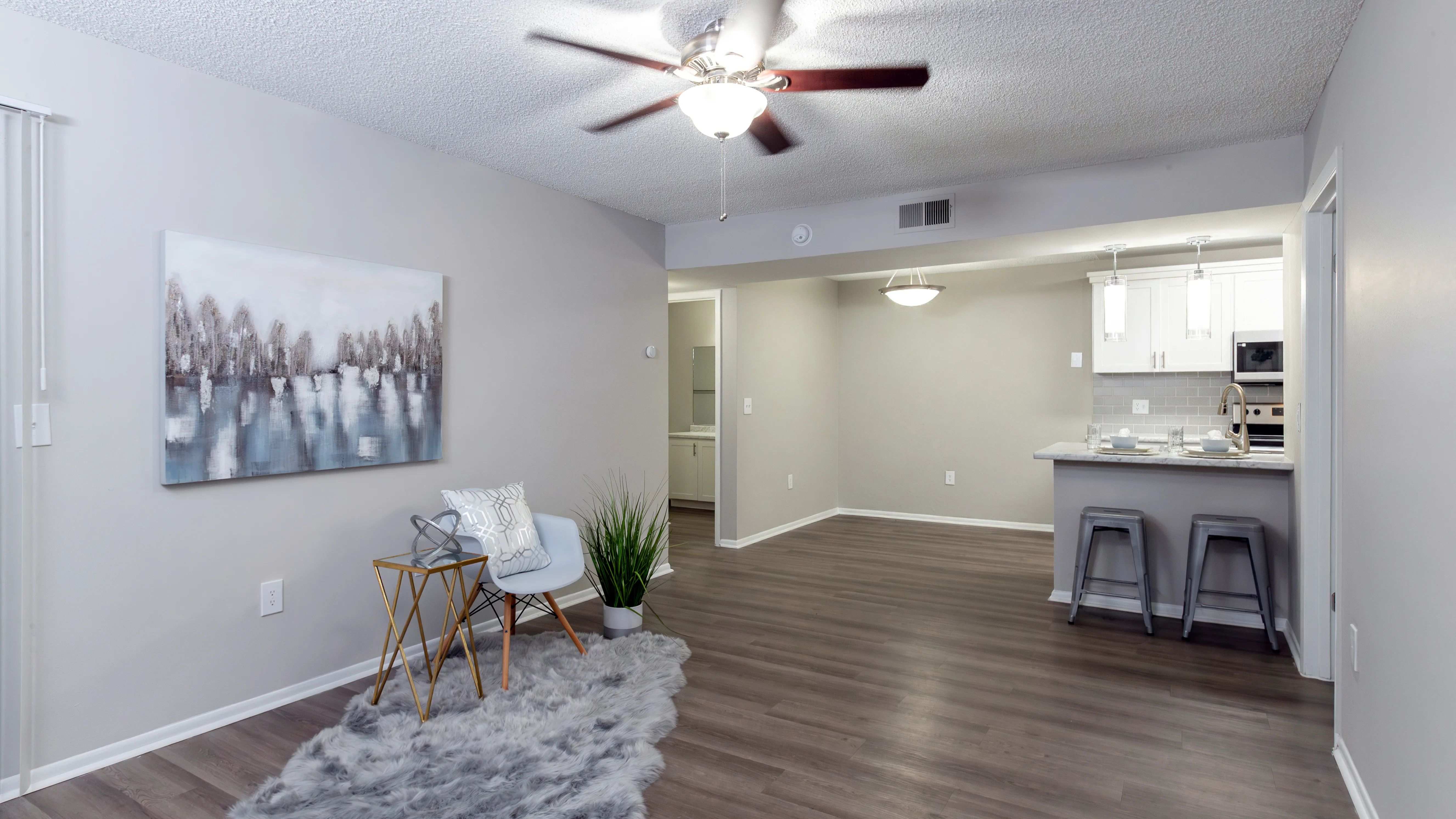 Spacious living rooms, where wood-style floors meet dancing ceiling fans in a cozy embrace.