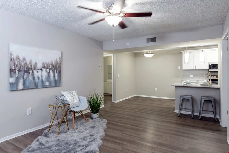 Spacious living rooms, where wood-style floors meet dancing ceiling fans in a cozy embrace.