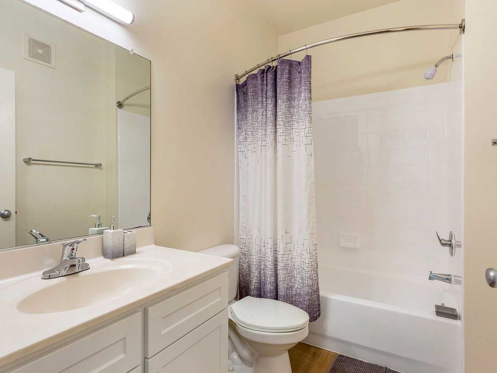 Renovated Package I bath with white cabinetry, white countertop, and hard surface plank flooring