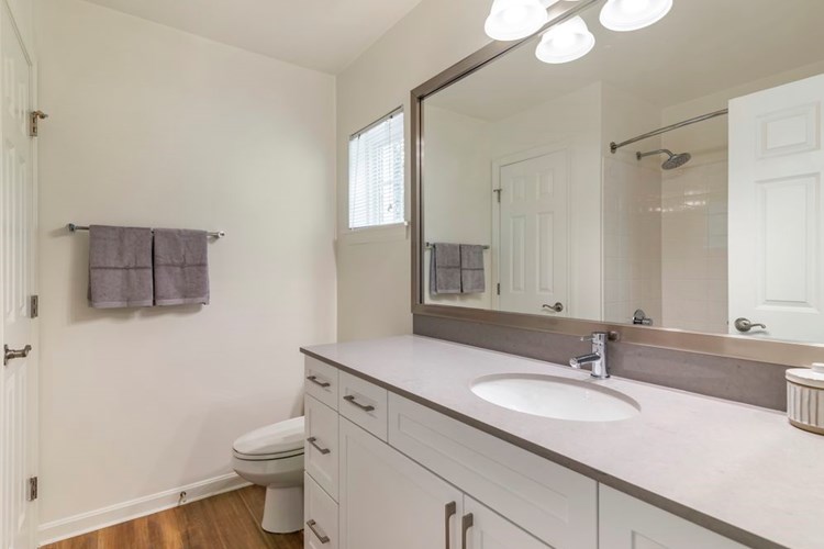 Renovated Package II bath with white cabinetry, grey quartz countertop, and hard surface flooring