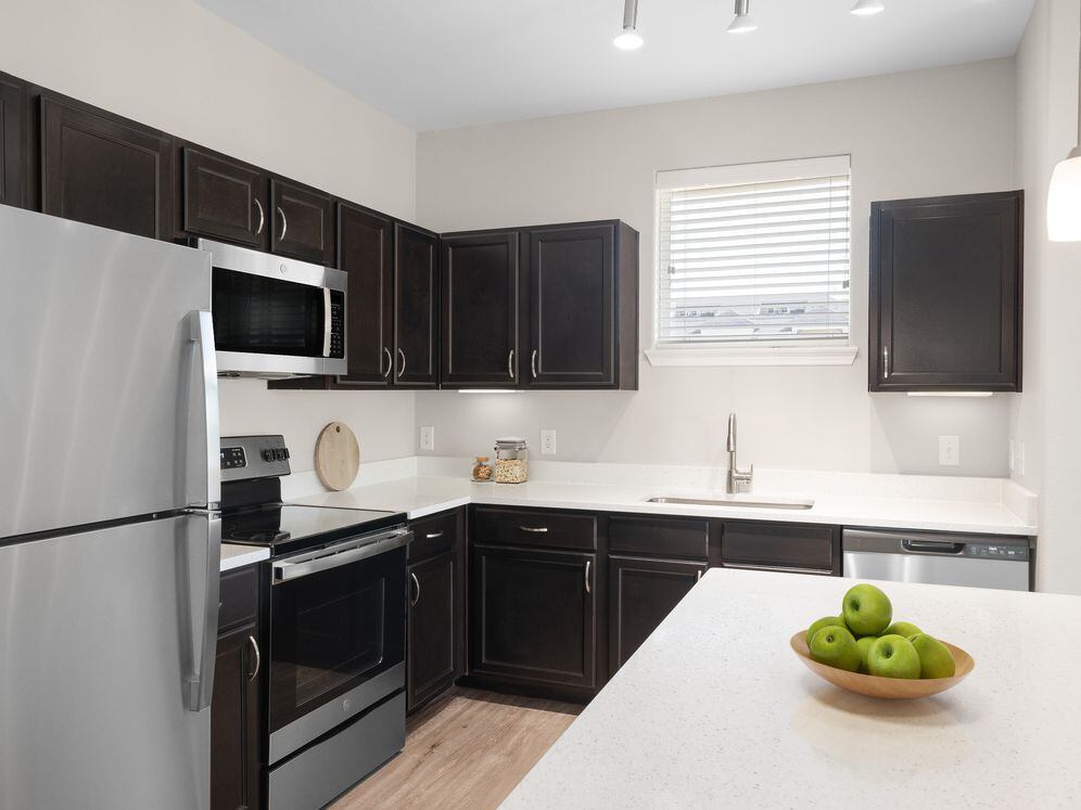 Kitchen with stainless steel appliances, quartz or granite countertop, espresso cabinetry, and hard surface vinyl plank flooring