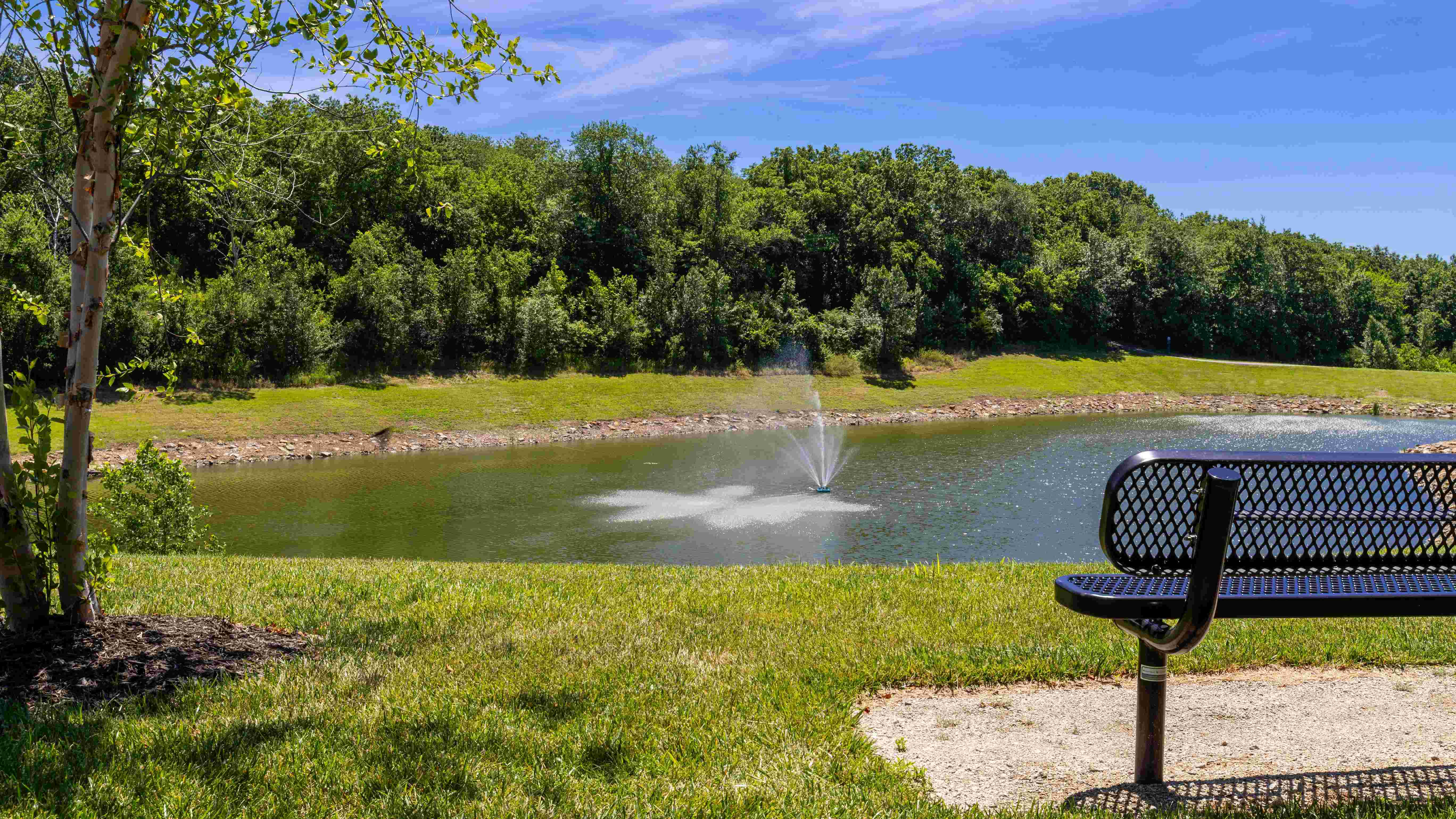 Relax by the serene lake where you can enjoy the soothing sounds of the fountain and the beauty of nature from a comfortable bench.