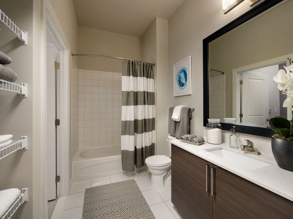 Bathroom with storage space, tile floor, European-style cabinetry, white countertop, shower with tile backsplash and hard surface flooring