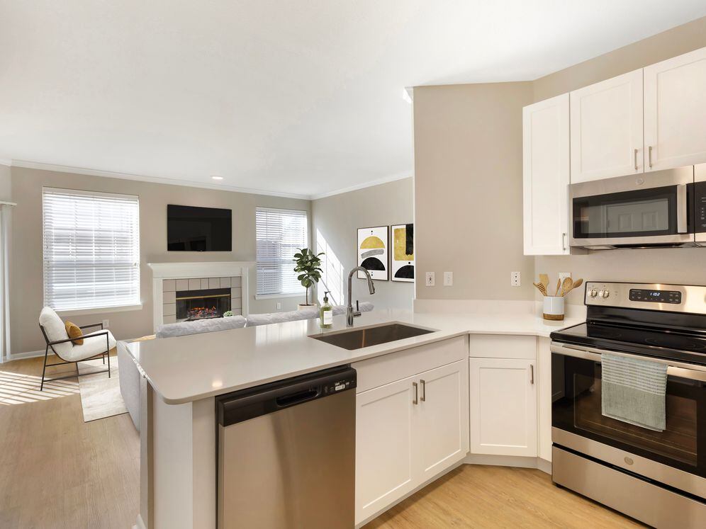 Renovated Package I kitchen with stainless steel appliances, white speckled quartz countertop, white cabinetry, and hard surface flooring