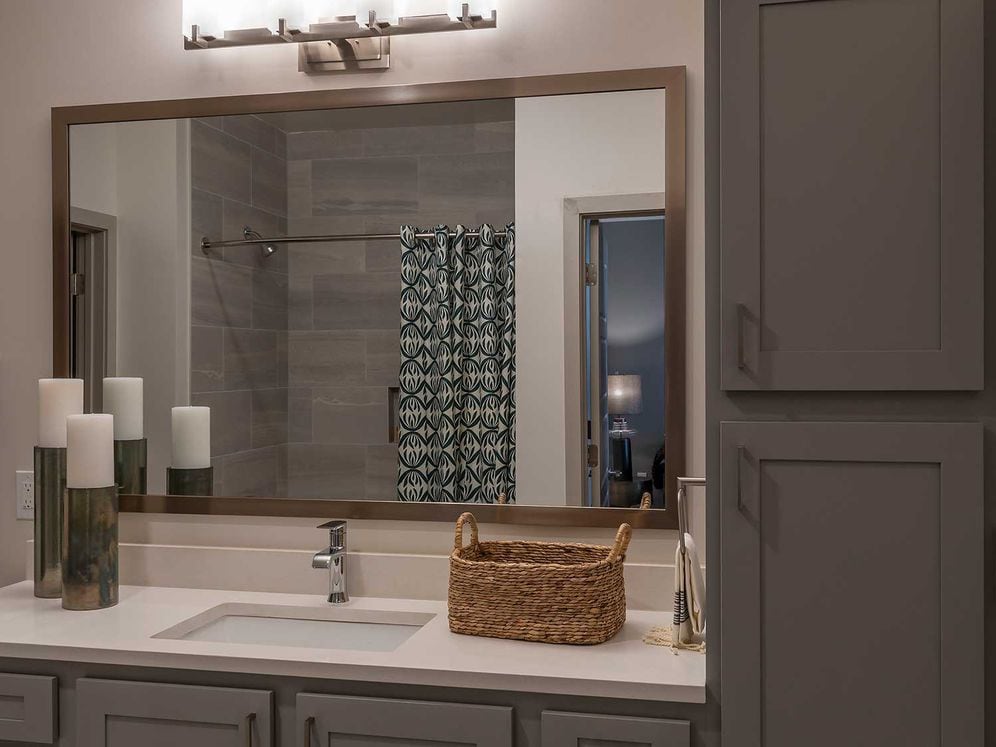 East Classic I bath with grey cabinetry, white granite countertops, stone shower, and hard surface plank flooring