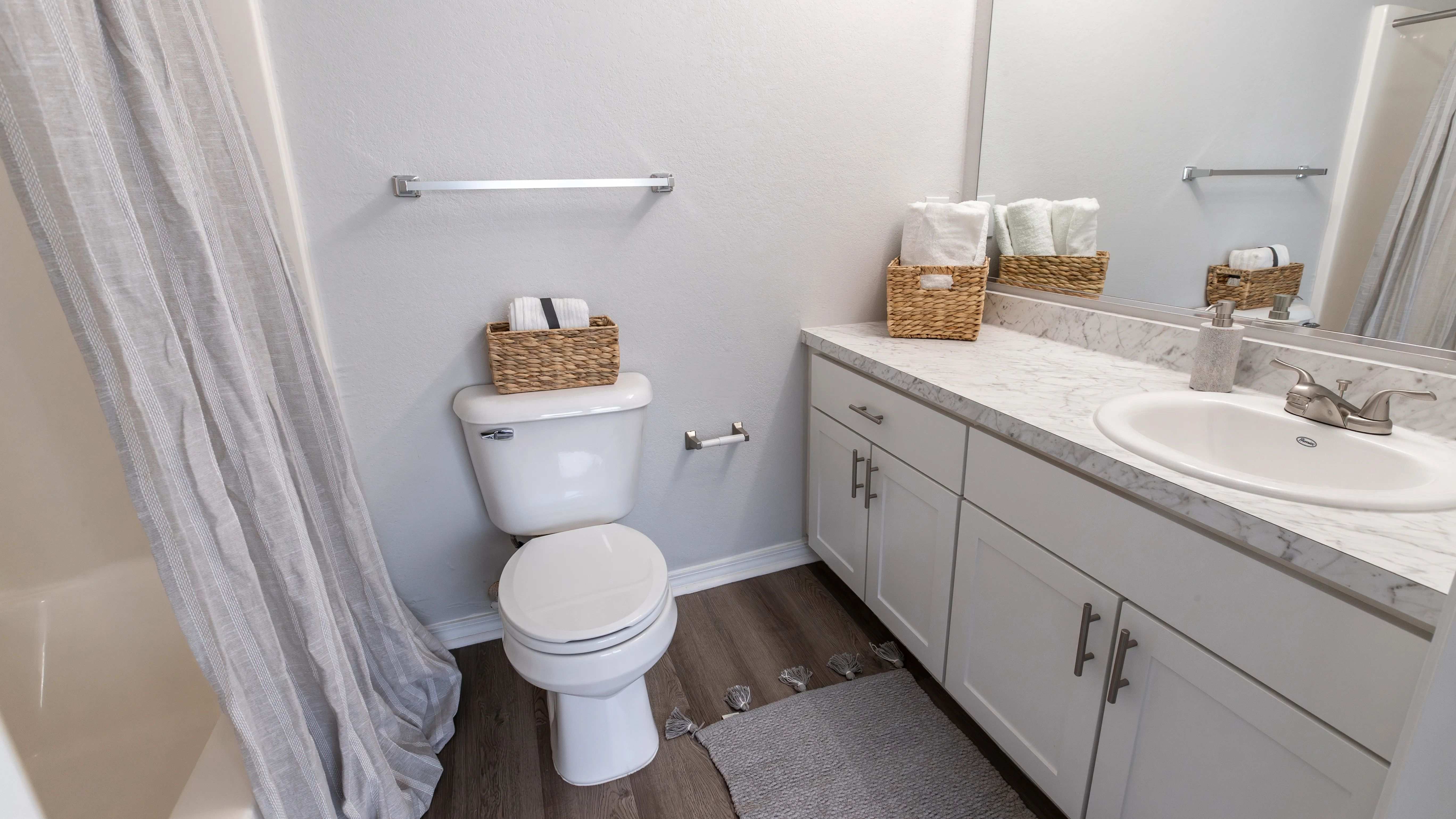Enjoy the clean and elegant design of this bathroom featuring granite-style countertops and ample storage.