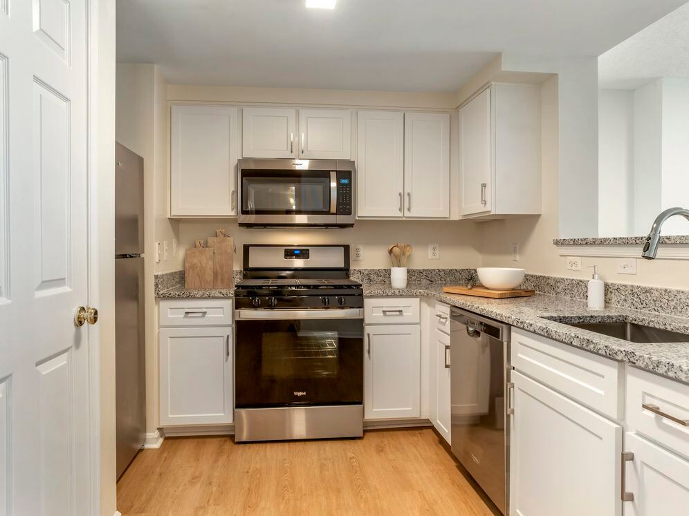 Renovated Package I kitchen with white cabinetry, granite countertops, stainless steel appliances, and hard surface flooring