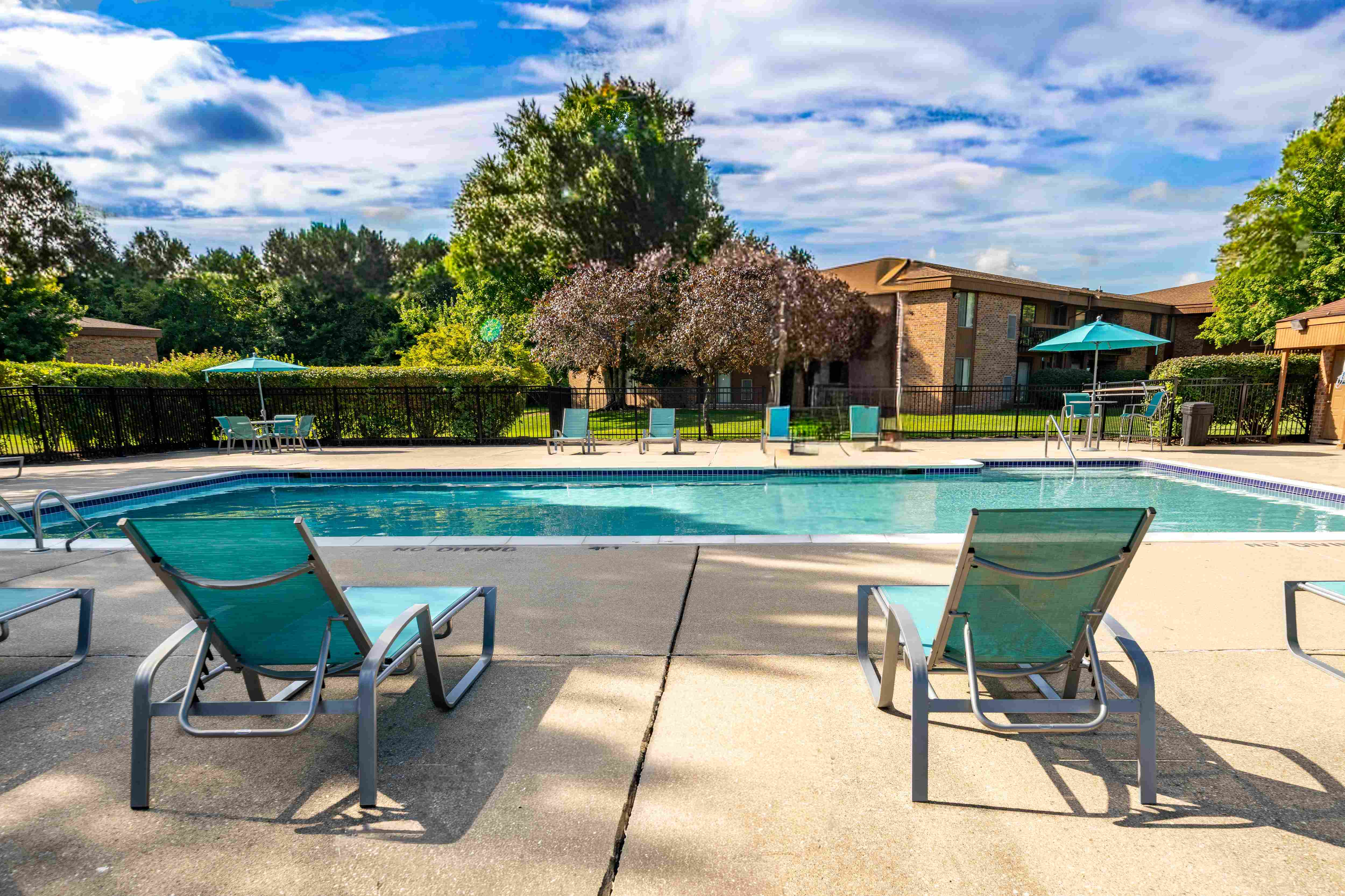 Heated pool equipped with comfy lounge chairs at Westwood Village Apartments in Westland, MI