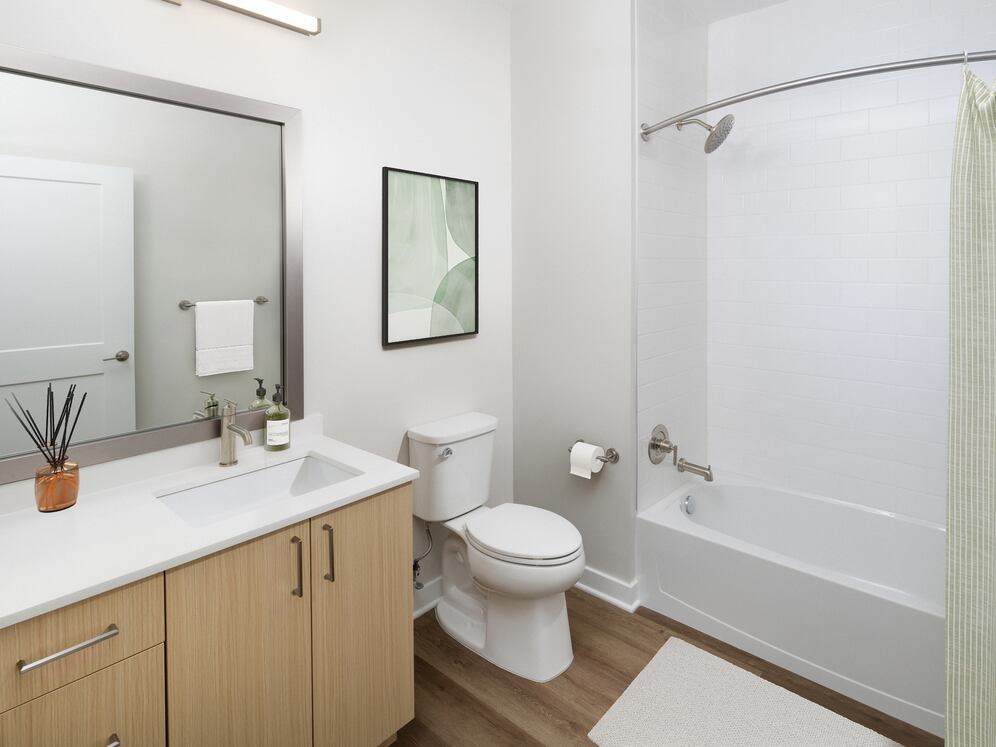 Upgrade Collection I bath with white quartz countertop, light oak cabinetry, and hard surface flooring