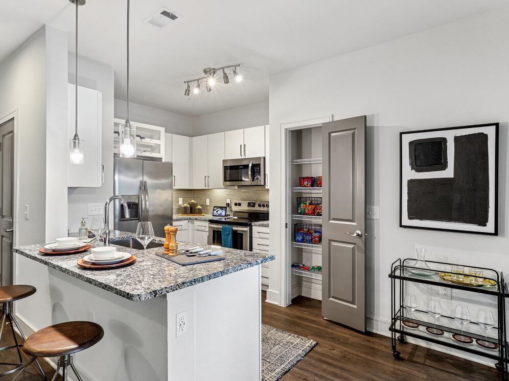 Kitchen with white cabinetry, speckled granite countertops, grey tile backsplash, stainless steel appliances, and hard surface flooring