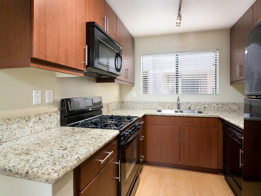 Classic Package I kitchen with chestnut cabinetry, beige speckled granite countertops, black appliances, and hard surface flooring