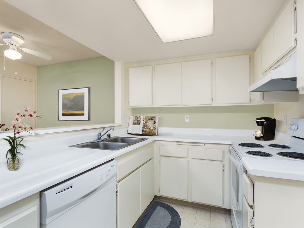 Classic Package kitchen with white appliances, white laminate countertops, white cabinetry, and vinyl flooring