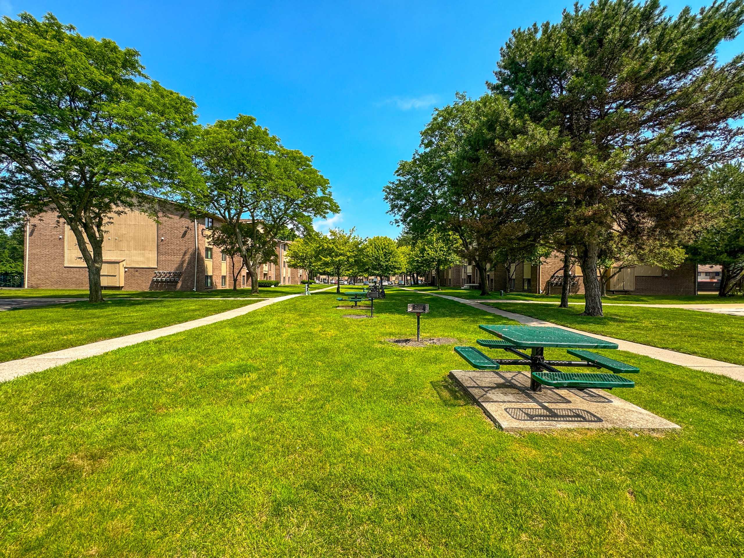 Expansive green space with picnic area at Woodland Villa Apartments in Westland, MI.