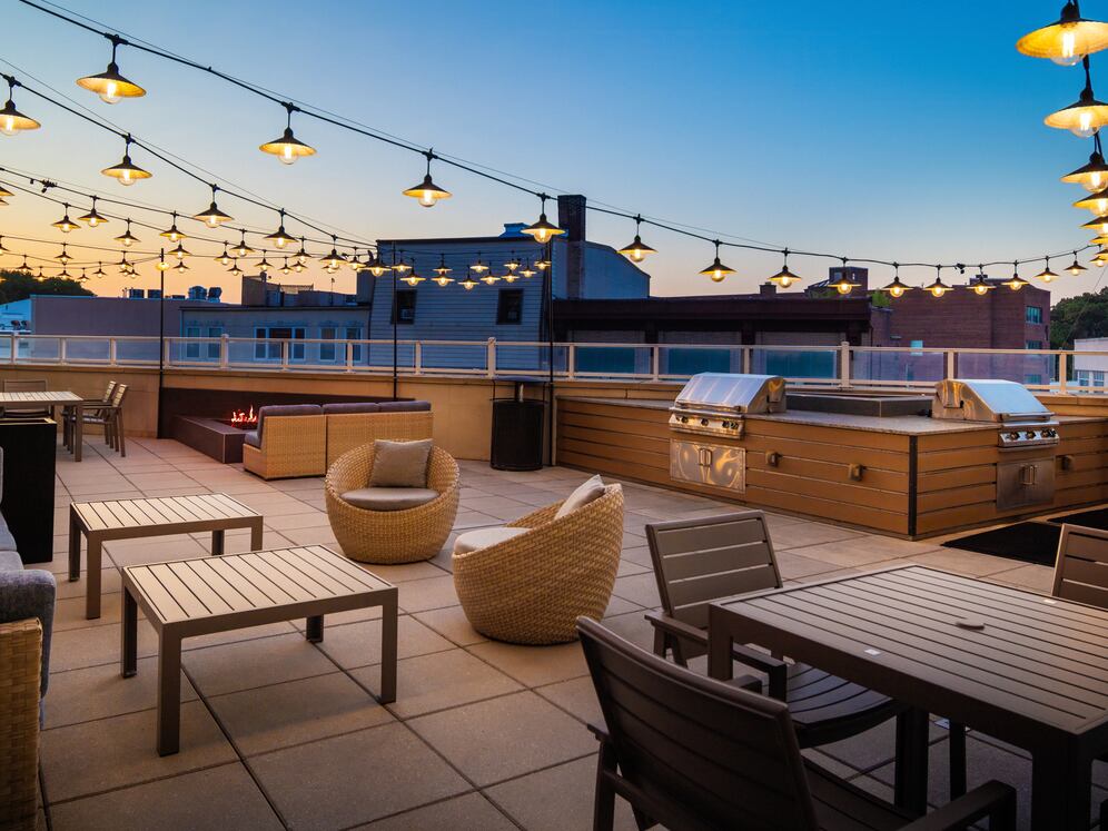 Rooftop patio with BBQ grills, lounge seating, and firepit