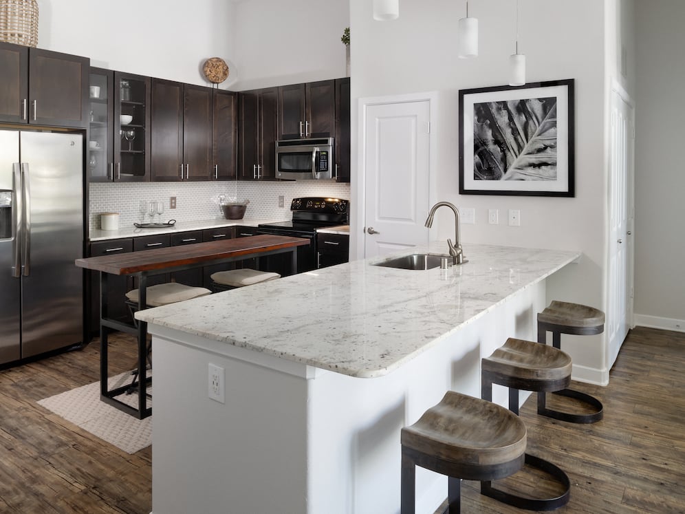 Kitchen with espresso cabinetry, granite countertops, tile backsplash, and stainless steel appliances