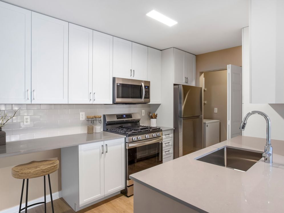 Upgrade Scheme II kitchen with white shaker cabinetry, grey quartz countertops, grey subway tile backsplash, stainless steel appliances, and hard surface flooring