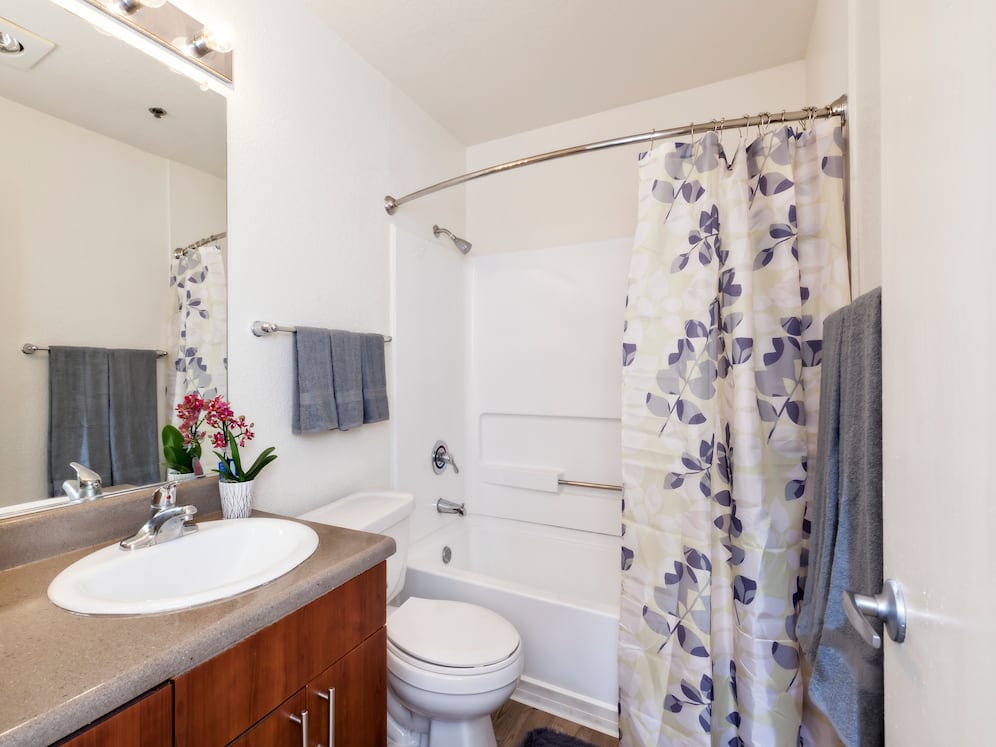 Classic Package bath with dark grey laminate countertop, cherry cabinetry, and hard surface flooring