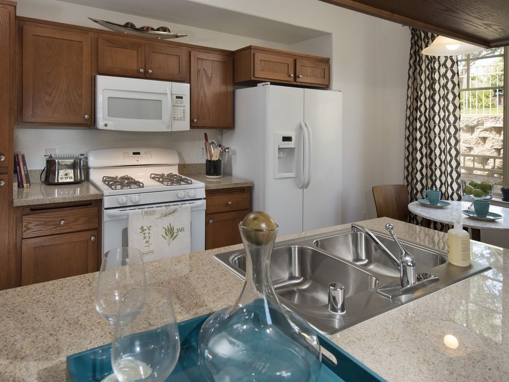 Classic Package I kitchen with maple cabinetry, beige speckled granite countertops, white appliances, and tile flooring