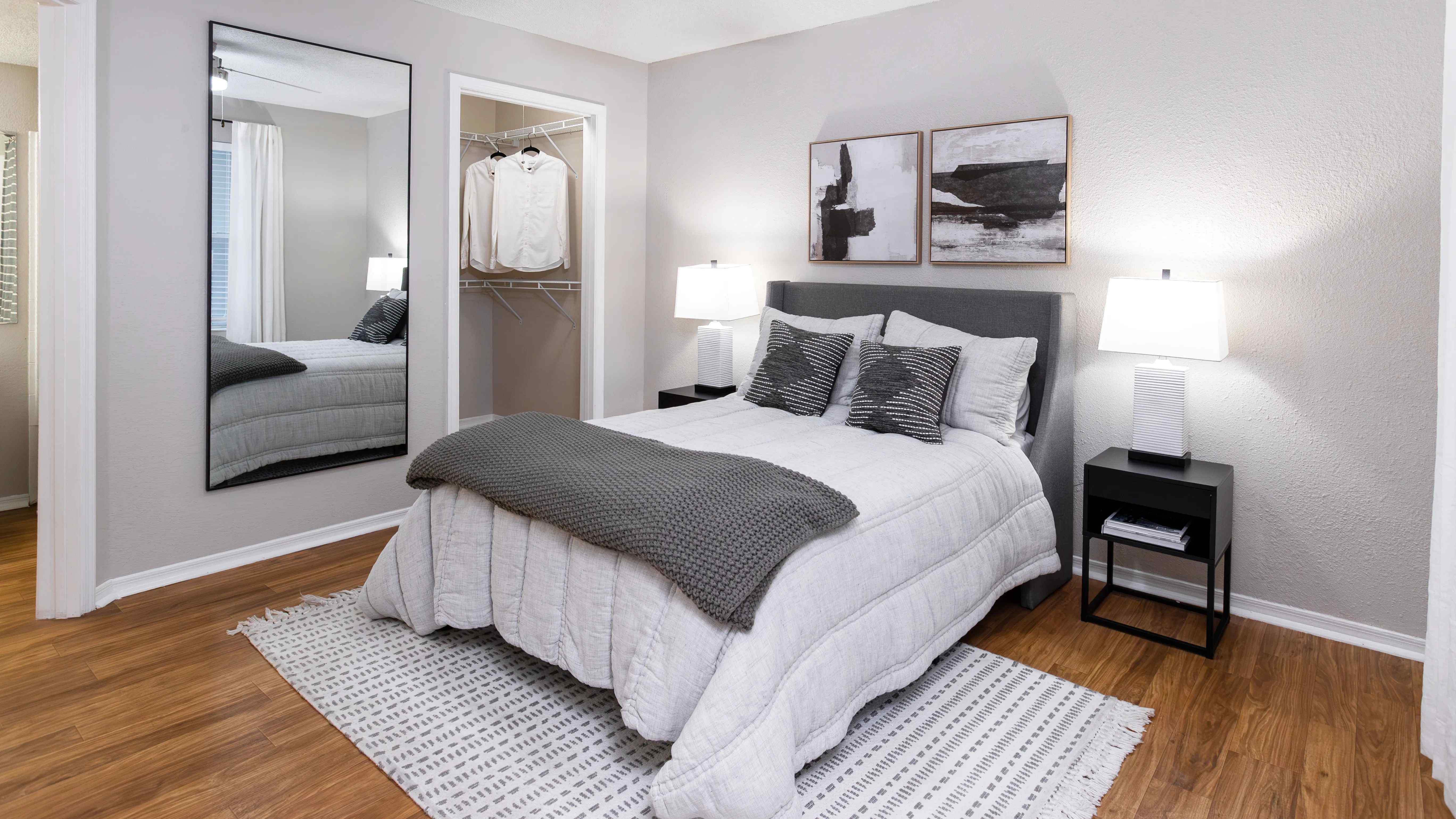 Unwind in a cozy bedroom featuring wood-style flooring, soft lighting, and a spacious walk-in closet.
