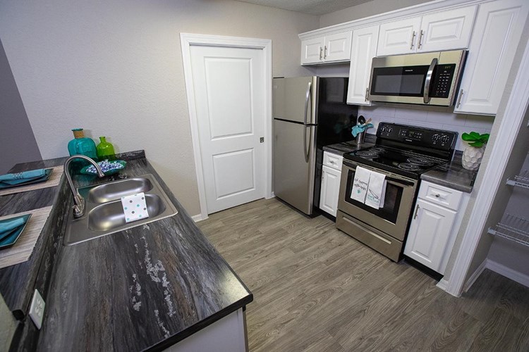 Select kitchens feature black-fusion countertops along with wood-style flooring, and stainless-steel appliances.