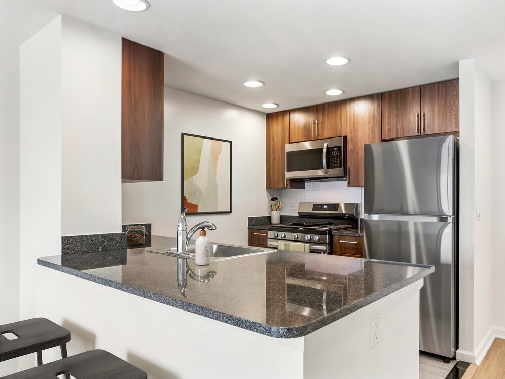 Updated Finishes kitchen with espresso cabinetry, dark speckled granite countertops, white tile backsplash, stainless steel appliances, and hard surface flooring