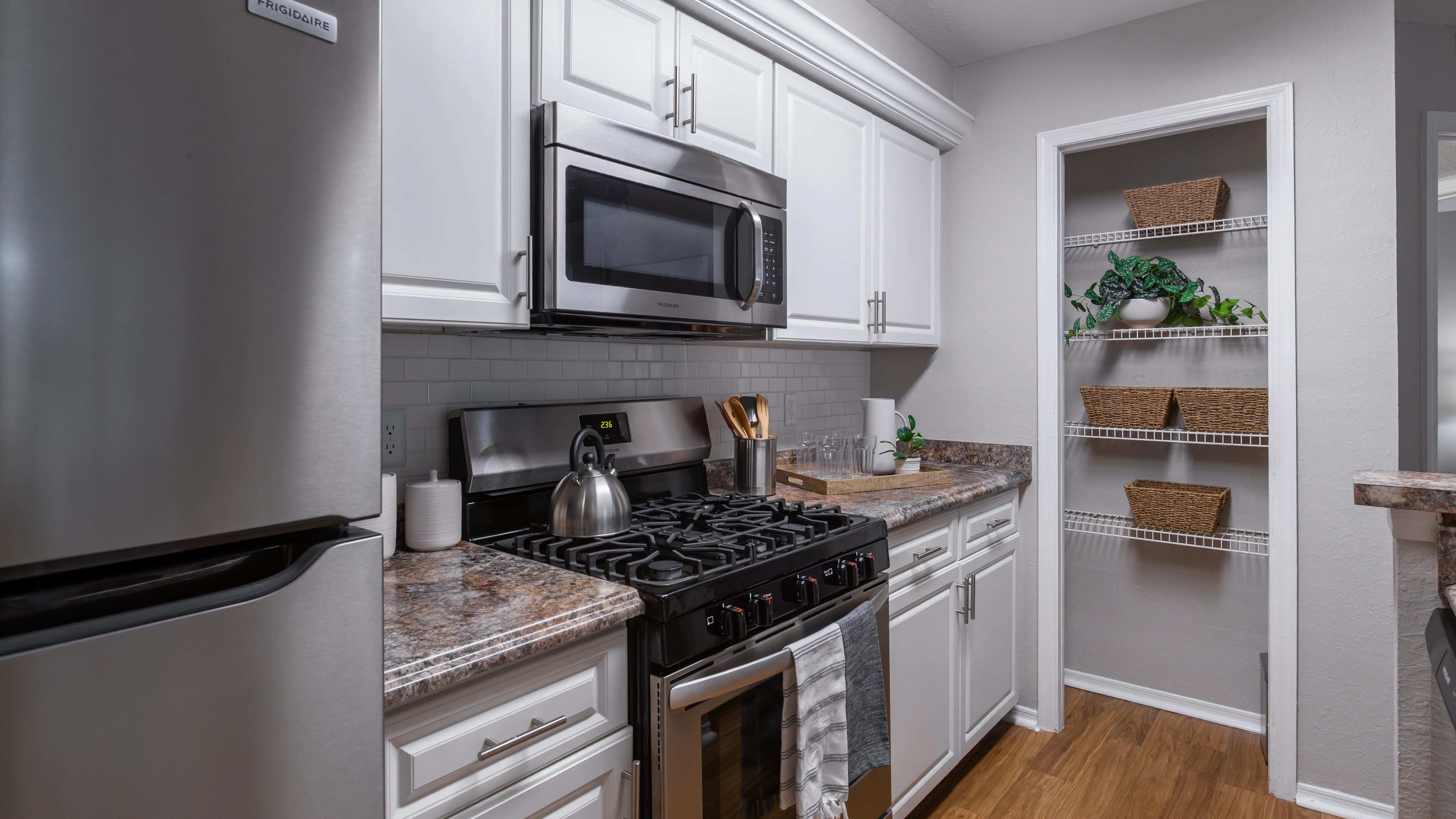 Fully equipped kitchen with stainless steel appliances, subway tile backsplash, and a convenient pantry—perfect for any home chef.