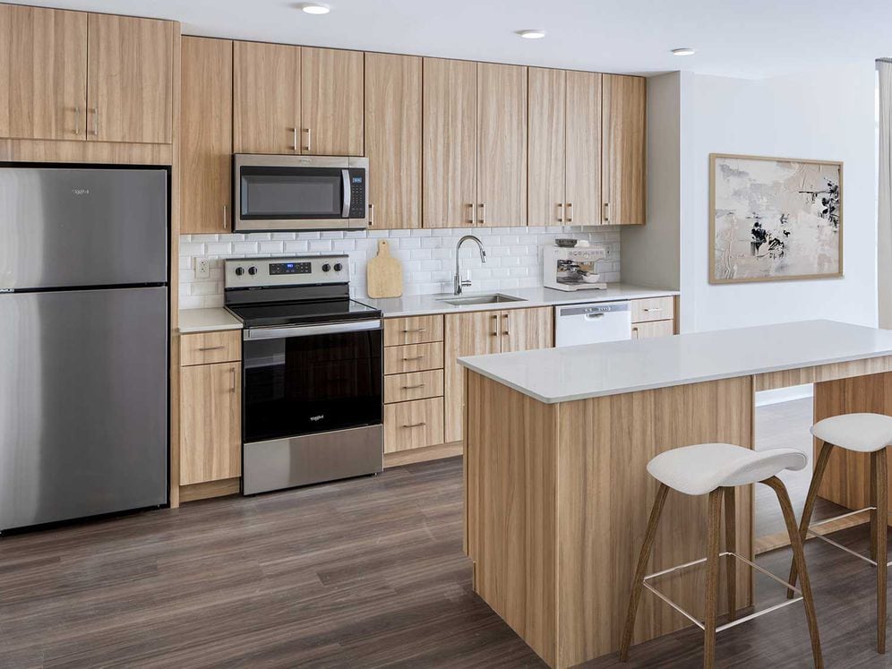 Design Collection II Kitchen with oak cabinetry, white tile backsplash, white quartz countertops, and stainless steel appliances