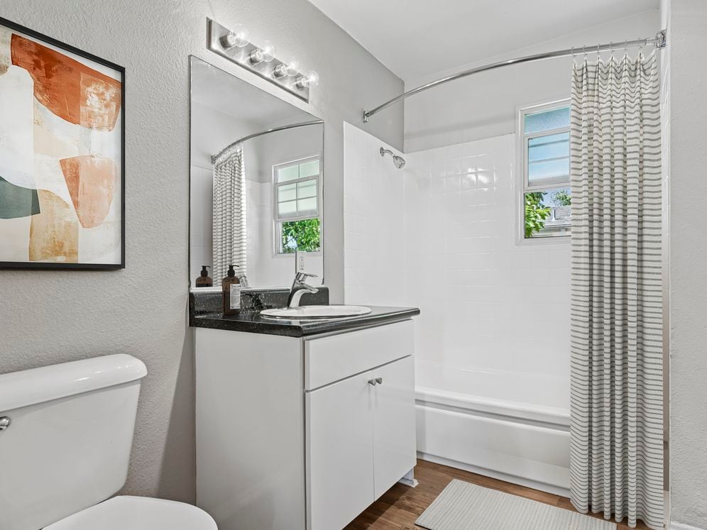 Bath with white cabinetry, black laminate countertops, and hard surface flooring