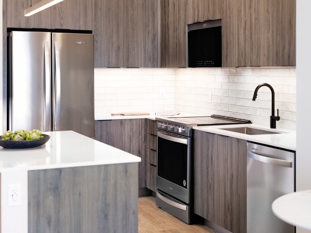 Upgrade Collection II kitchen with espresso cabinetry, white tile backsplash, stainless steel appliances, and hard-surface vinyl plank flooring