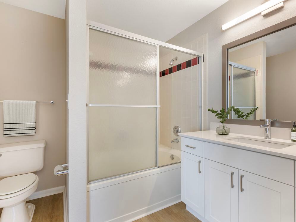 Renovated Package I bath with white speckled quartz countertop, white cabinetry, and hard surface flooring