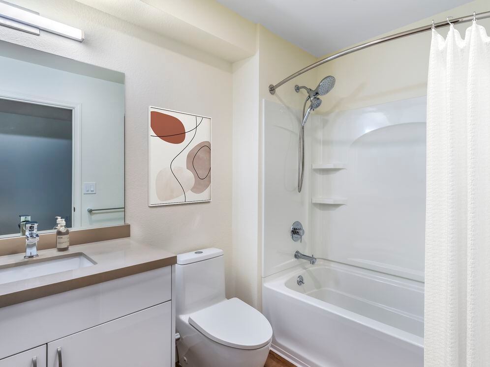 Renovated Package II bath with beige quartz countertops, white cabinetry, and hard surface flooring