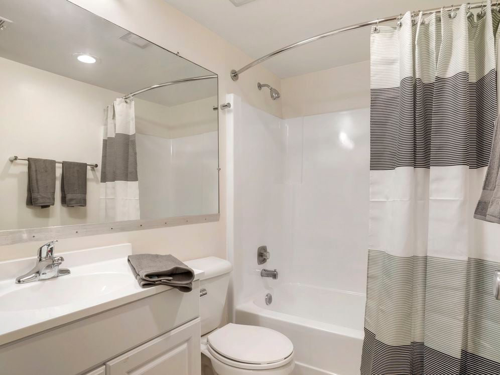 Renovated Package II bath featuring white cabinetry and countertops