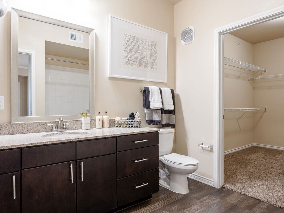Baths with dark cabinetry, beige speckled granite countertops, and hard surface flooring