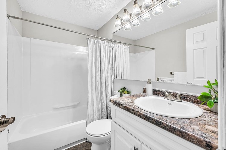 Newly renovated bathrooms featuring granite-style countertops, large mirrors, and wood-style flooring.