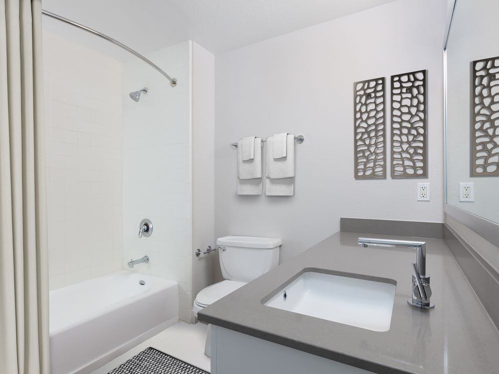 Renovated Phase I bath with quartz countertops and white cabinetry