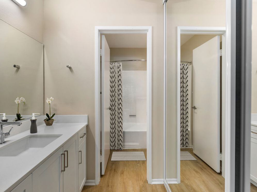 Renovated Package I bath with white quartz countertops, white cabinetry, and hard surface flooring