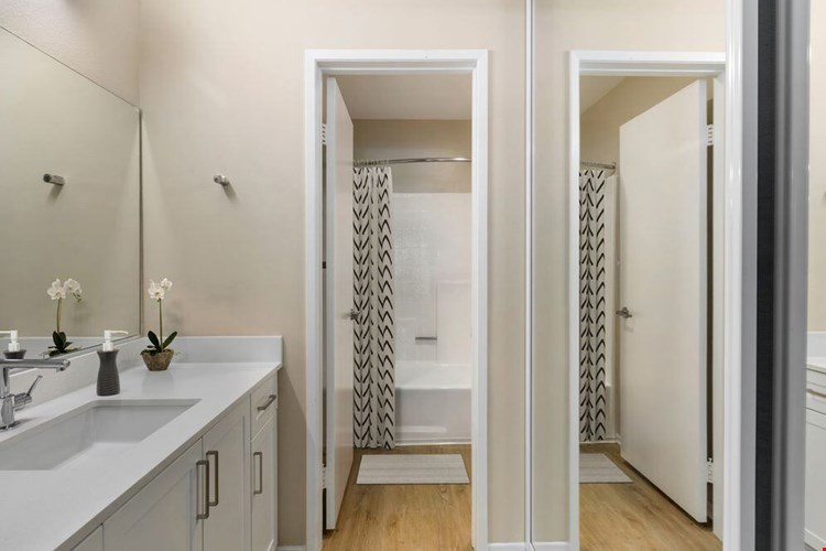 Renovated Package I bath with white quartz countertops, white cabinetry, and hard surface flooring