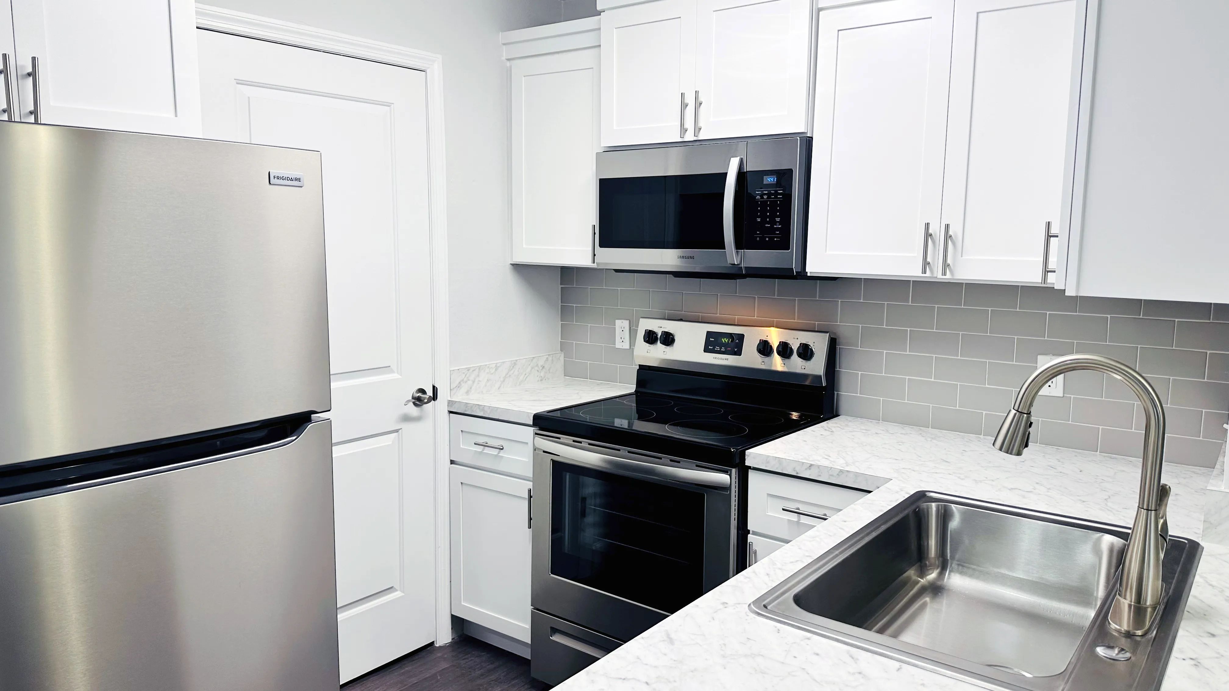 Indulge in our premier kitchens featuring white shaker cabinetry, grey subway tile backsplashes, and gleaming stainless-steel appliances through stunning renovations.   