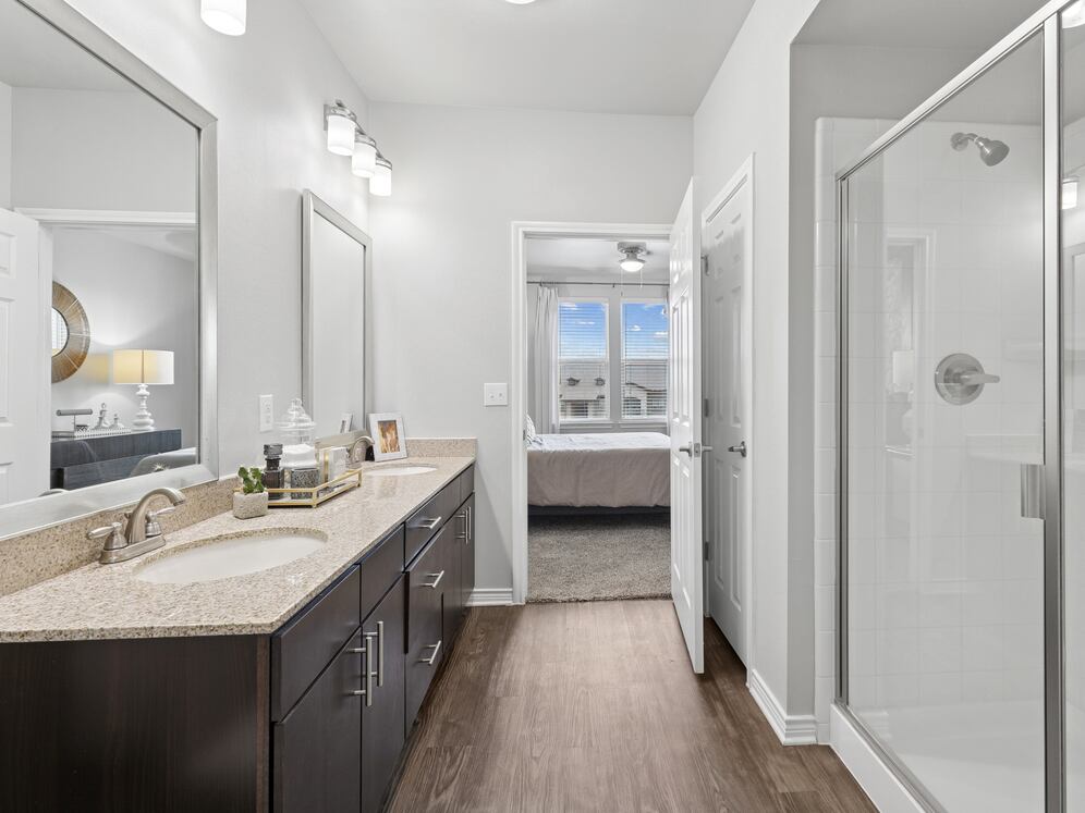Bath with dark cabinetry, beige speckled granite countertops, and hard surface flooring