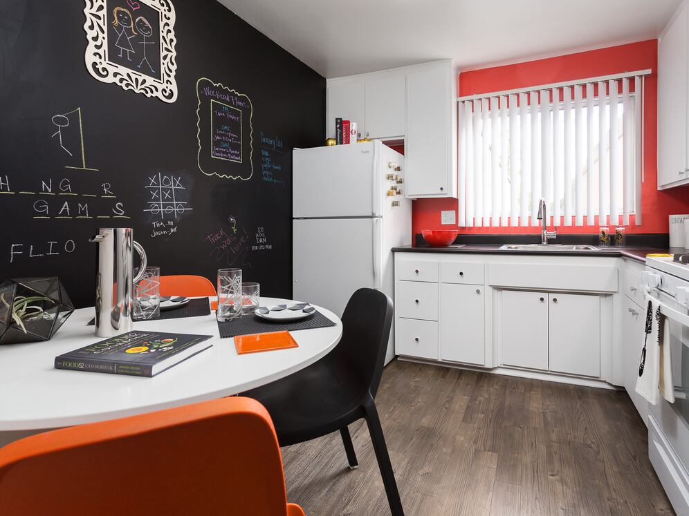 Classic Package II kitchen with white or black appliances, black laminate countertops, white cabinetry, and hard surface flooring (select homes)