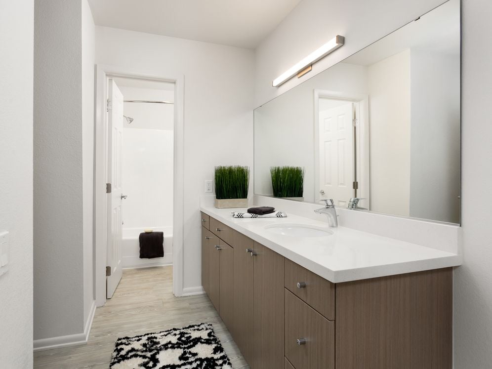 Renovated Package II bath with tan cabinetry, white quartz countertops, and hard surface plank flooring