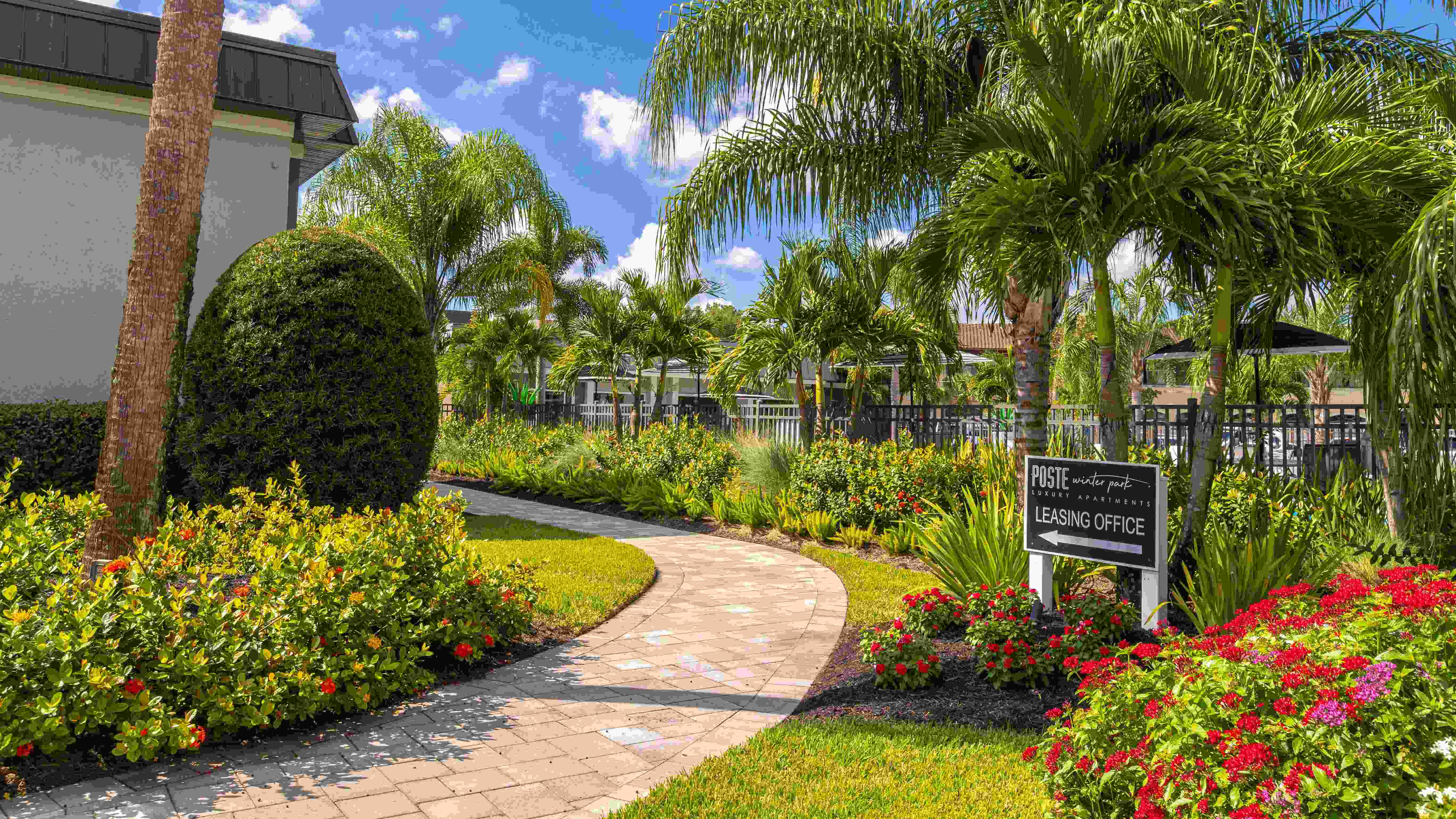 Stroll through the vibrant and lushly landscaped walkway leading to the leasing office. Surrounded by tropical plants and greenery, this inviting path sets the tone for a welcoming and serene community.