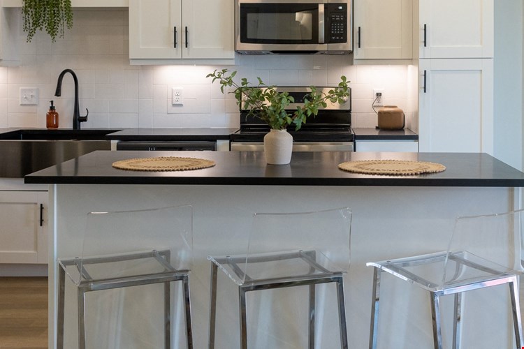 a kitchen with white cabinets and a black counter top