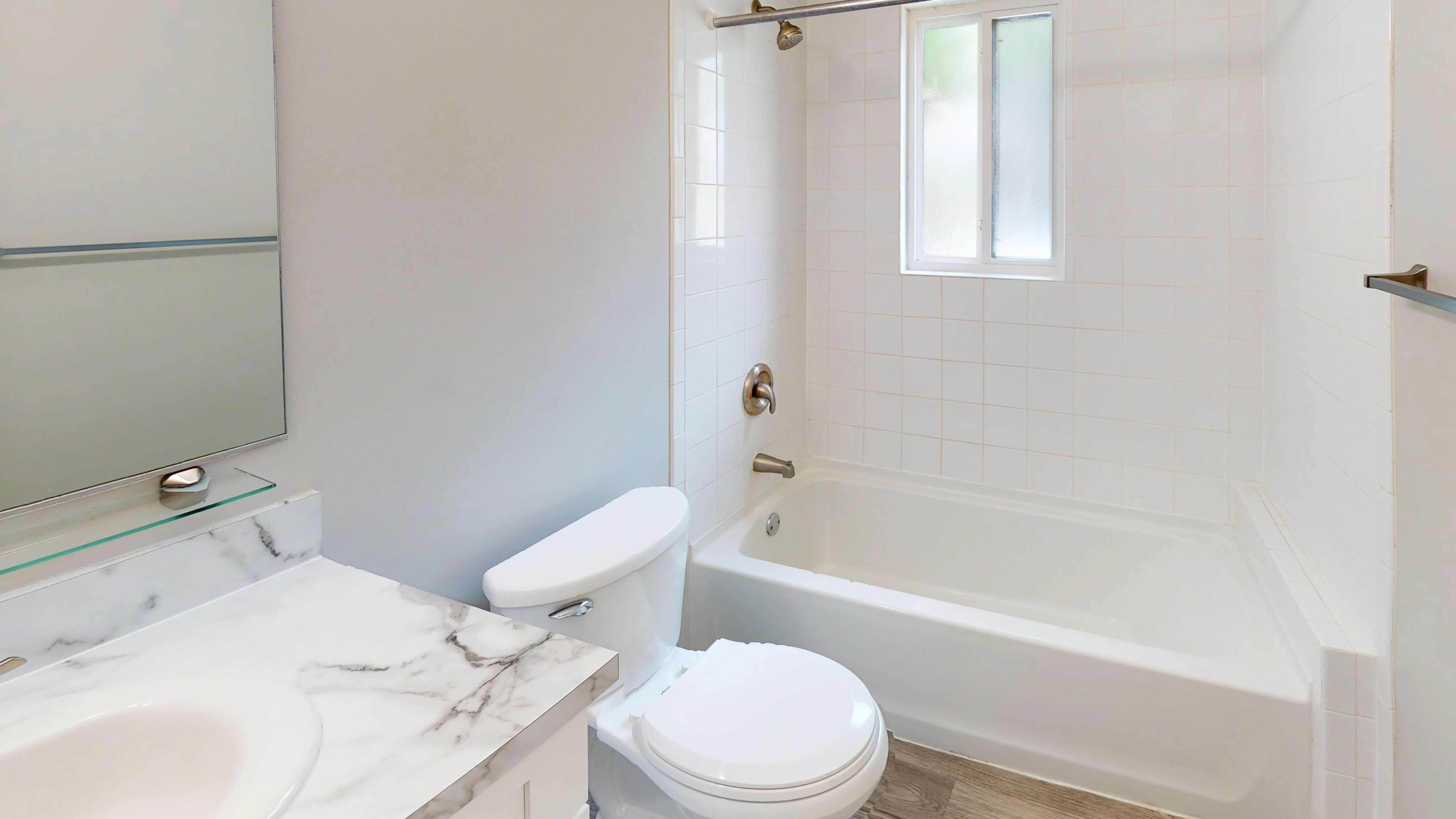 Refresh and recharge in an updated bathroom featuring a marble-inspired vanity countertop, bright finishes, and a beautifully tiled tub and shower.