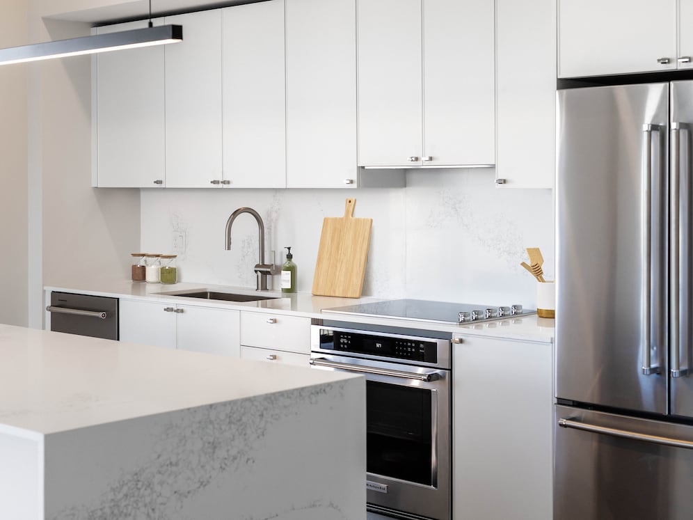 Signature Collection kitchen with white cabinetry, white marbled quartz countertop and backsplash, wine fridge, and upgraded stainless steel appliances