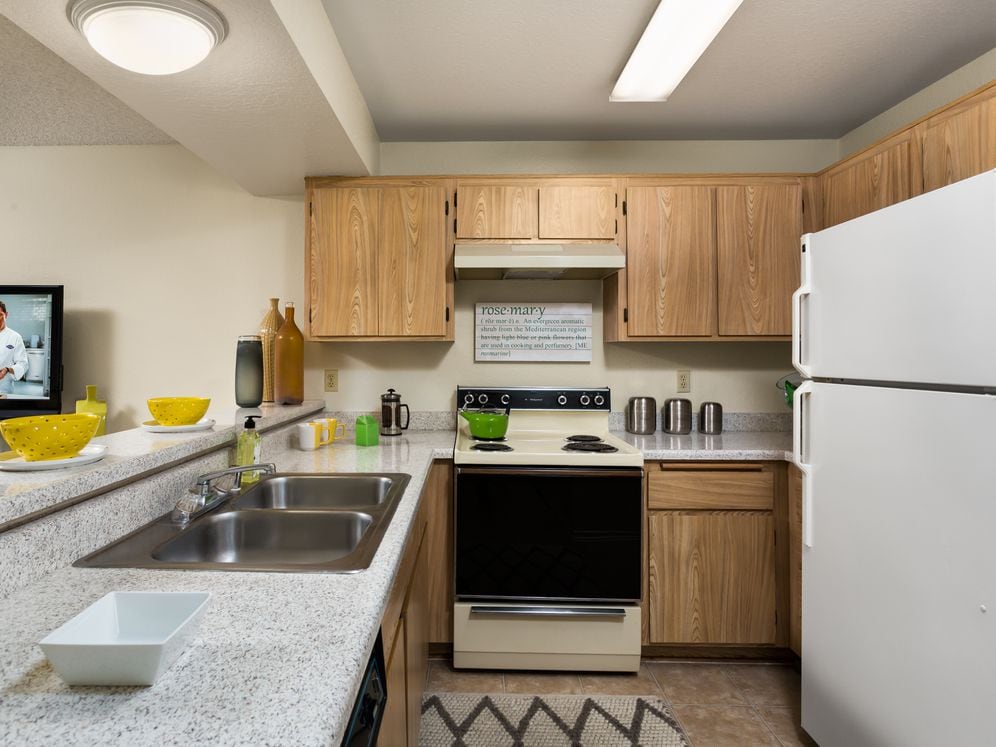 Classic Package kitchen with white appliances, oak cabinetry, white speckled granite countertops, and tile flooring