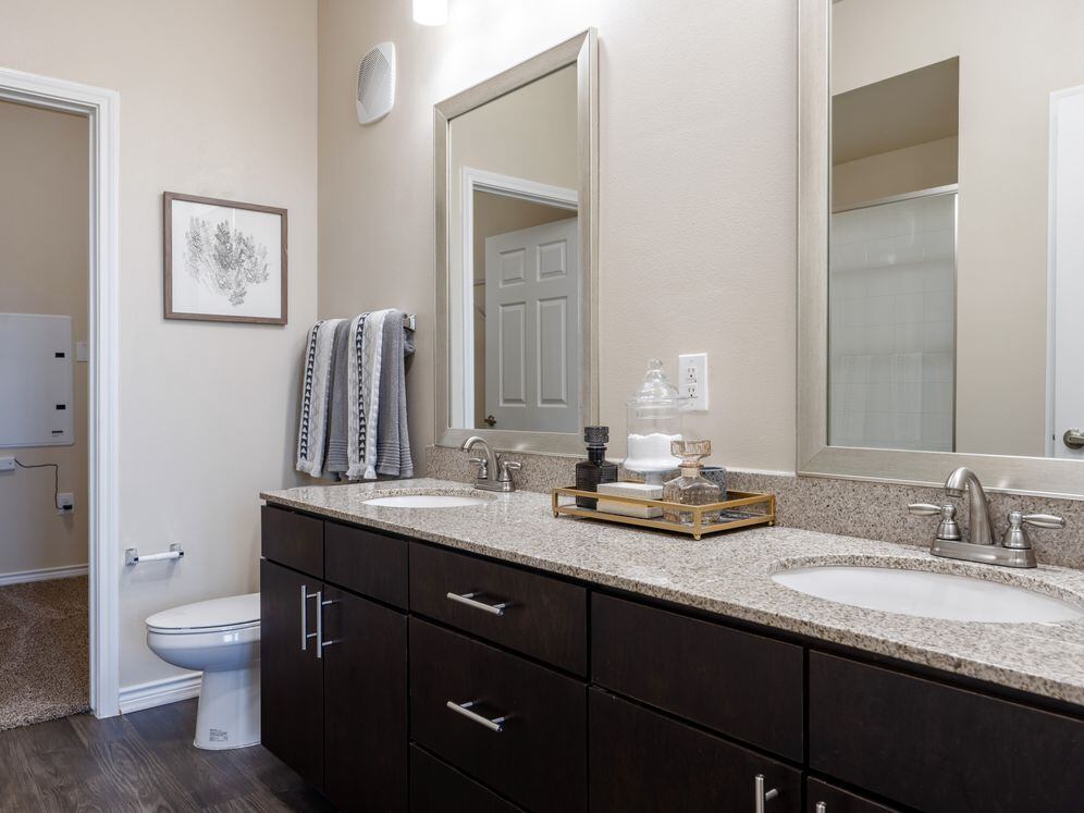 Baths with dark cabinetry, beige speckled granite countertops, and hard surface flooring