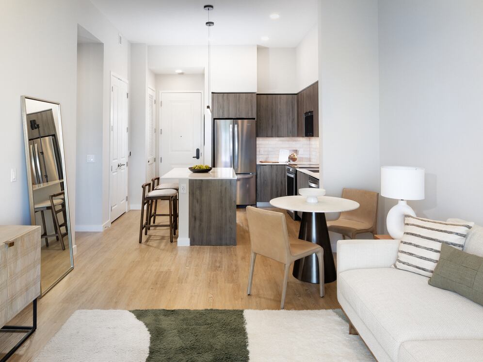 Living, dining, and kitchen space with espresso cabinetry, white tile backsplash, white quartz countertop, and hard-surface vinyl plank flooring