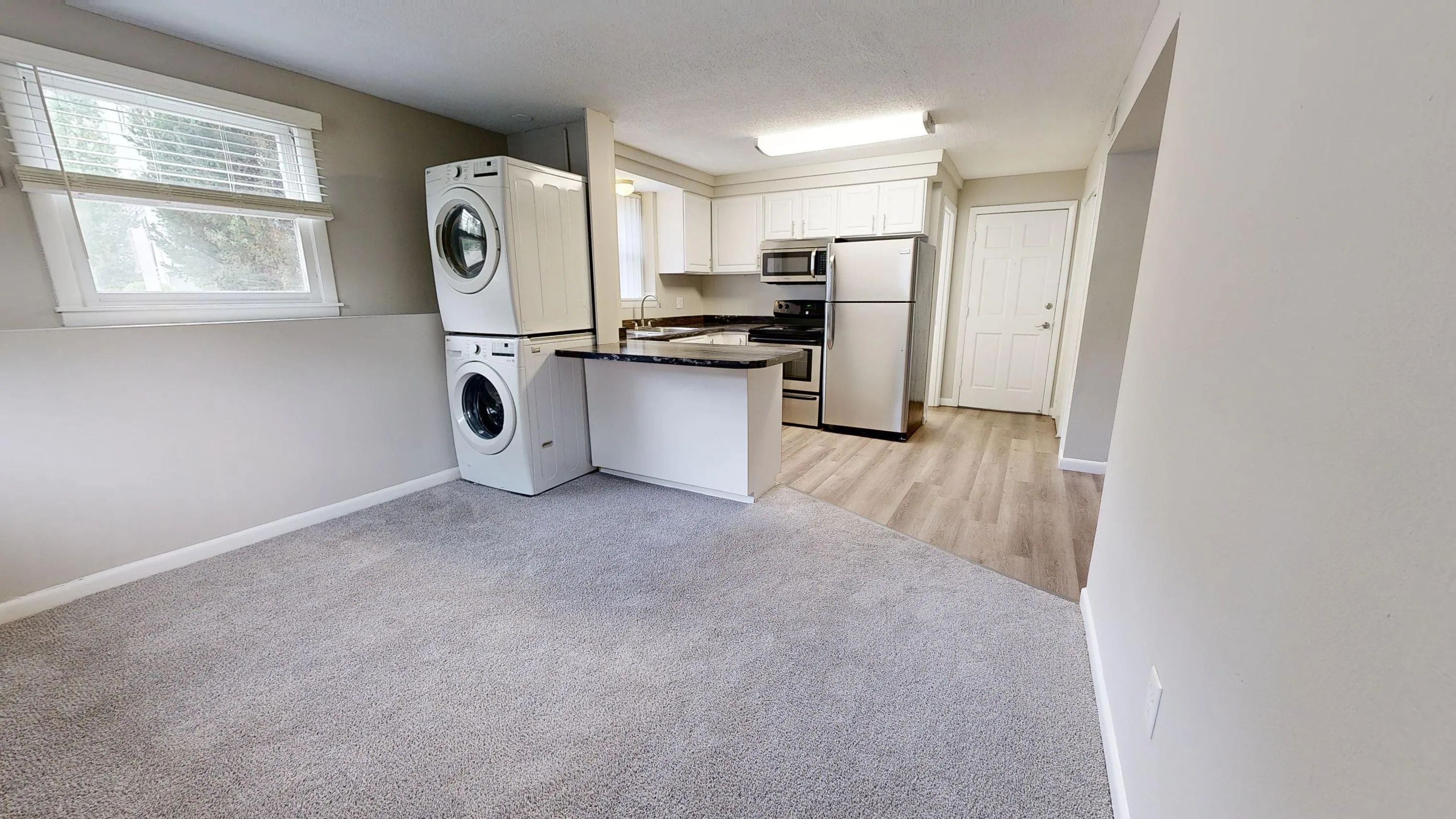 Enjoy the open-concept living space in The Valley floor plan at Alpine Commons Apartments. Featuring a modern kitchen with stainless steel appliances, in-unit washer and dryer, and cozy carpeted living area.
